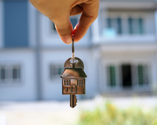 A hand holding out a set of keys to a new property where the buyer had to decide between a deposit bond vs bank guarantee as part of their property buying decision.