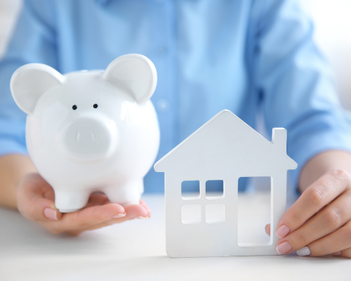 Hands holding a model house and a piggy bank, symbolising the financial planning involved in understanding how deposit bonds work.