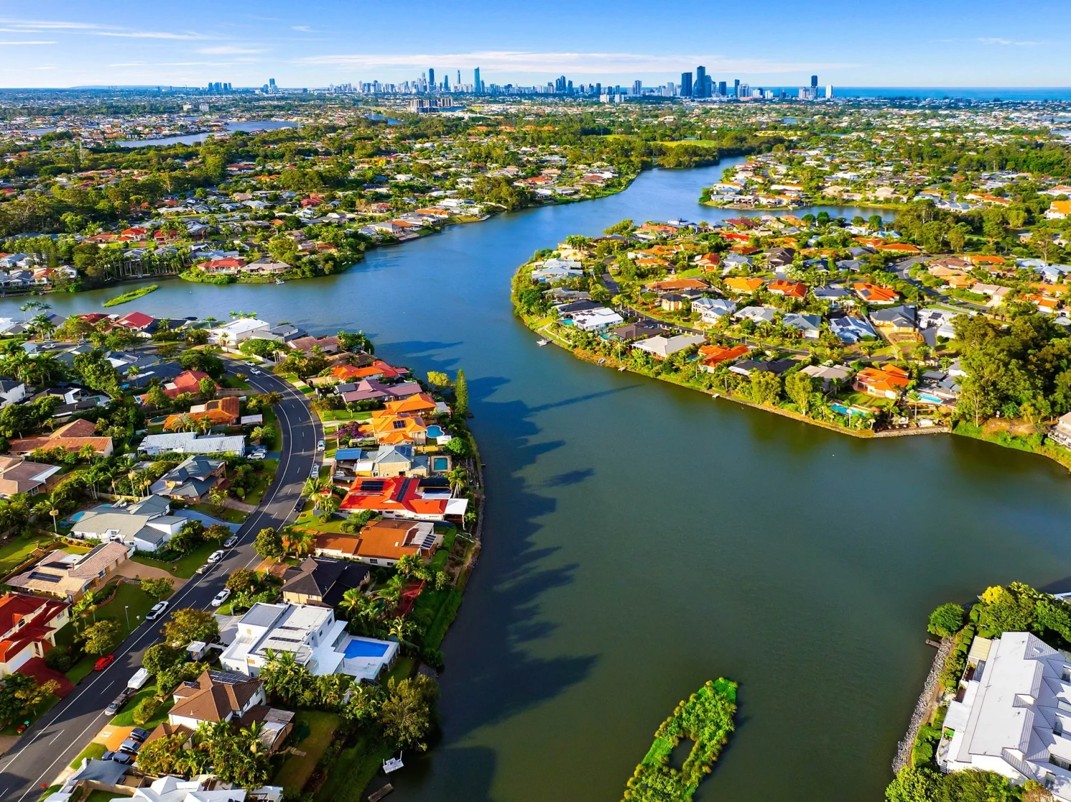 Aerial Robina waterfront properties with canals and established neighbourhoods with a city skyline backdrop